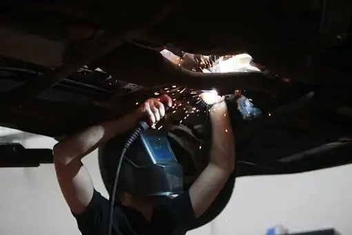 Autonasentaja hitsaa auton pohjaa